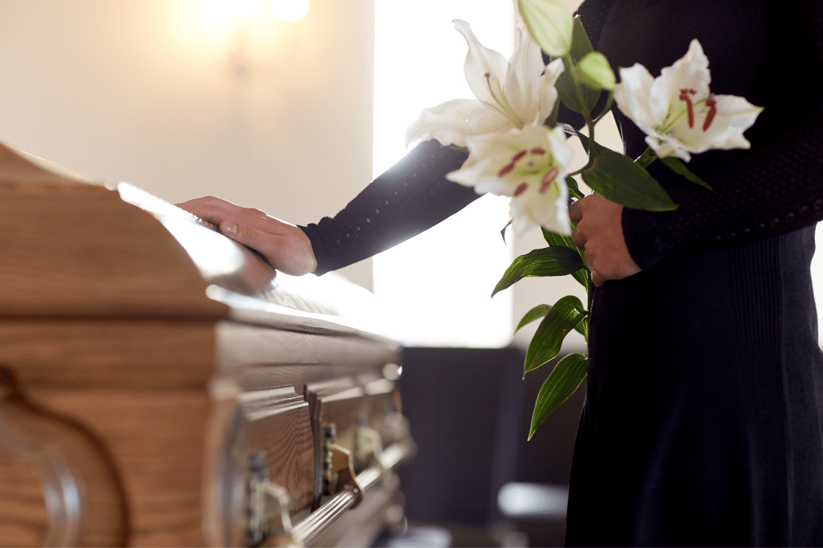 graphic woman holding flowers and putting hand on casket